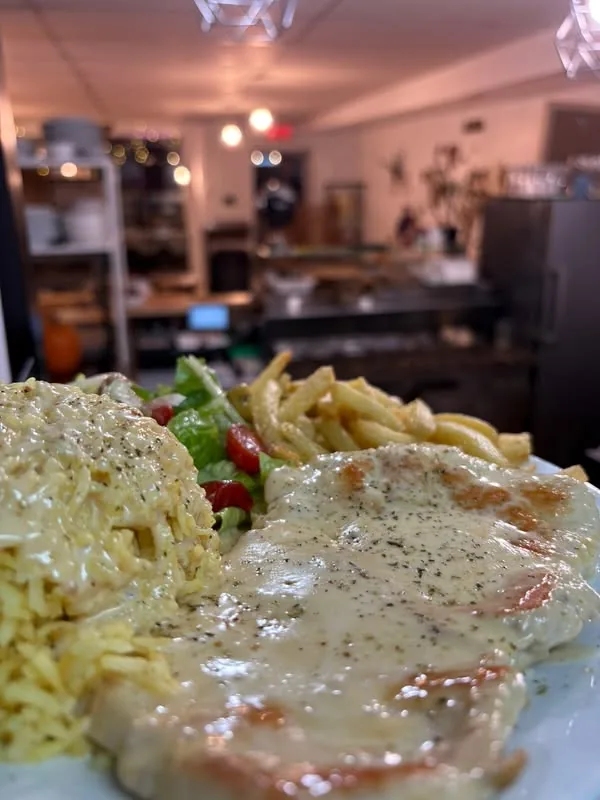 Une assiette d'escalope de poulet à la crème avec riz, salade et frites, photographiée dans la cuisine du restaurant